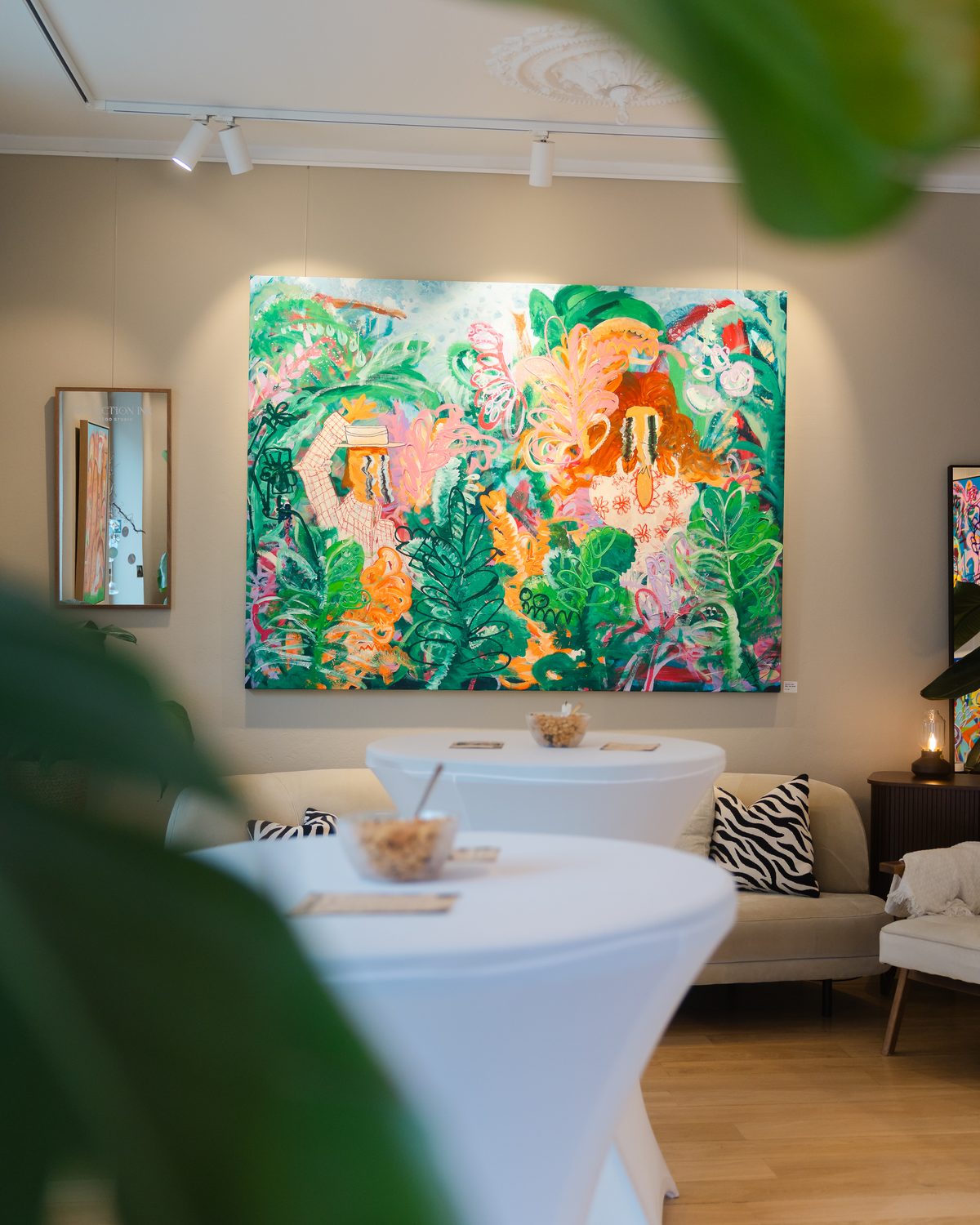 Lyst studio med stort fargerikt maleri og runde bord