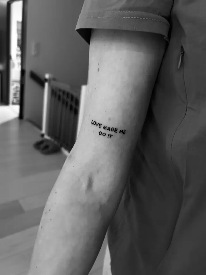 Teksten «Love made me do it» på overarmen, fineline av Sandra