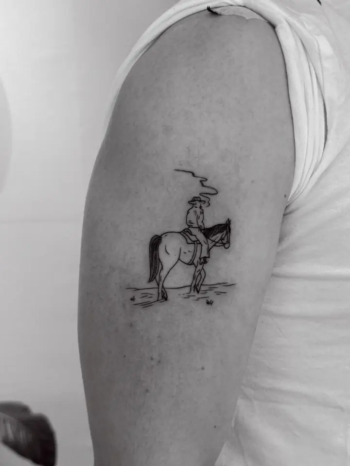 Cowboy på hest på overarmen, blackwork av Vilde
